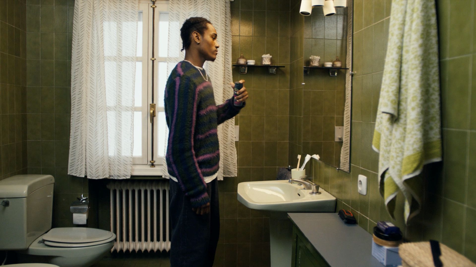 Um homem usando um desodorante Axe em frente ao espelho do banheiro.