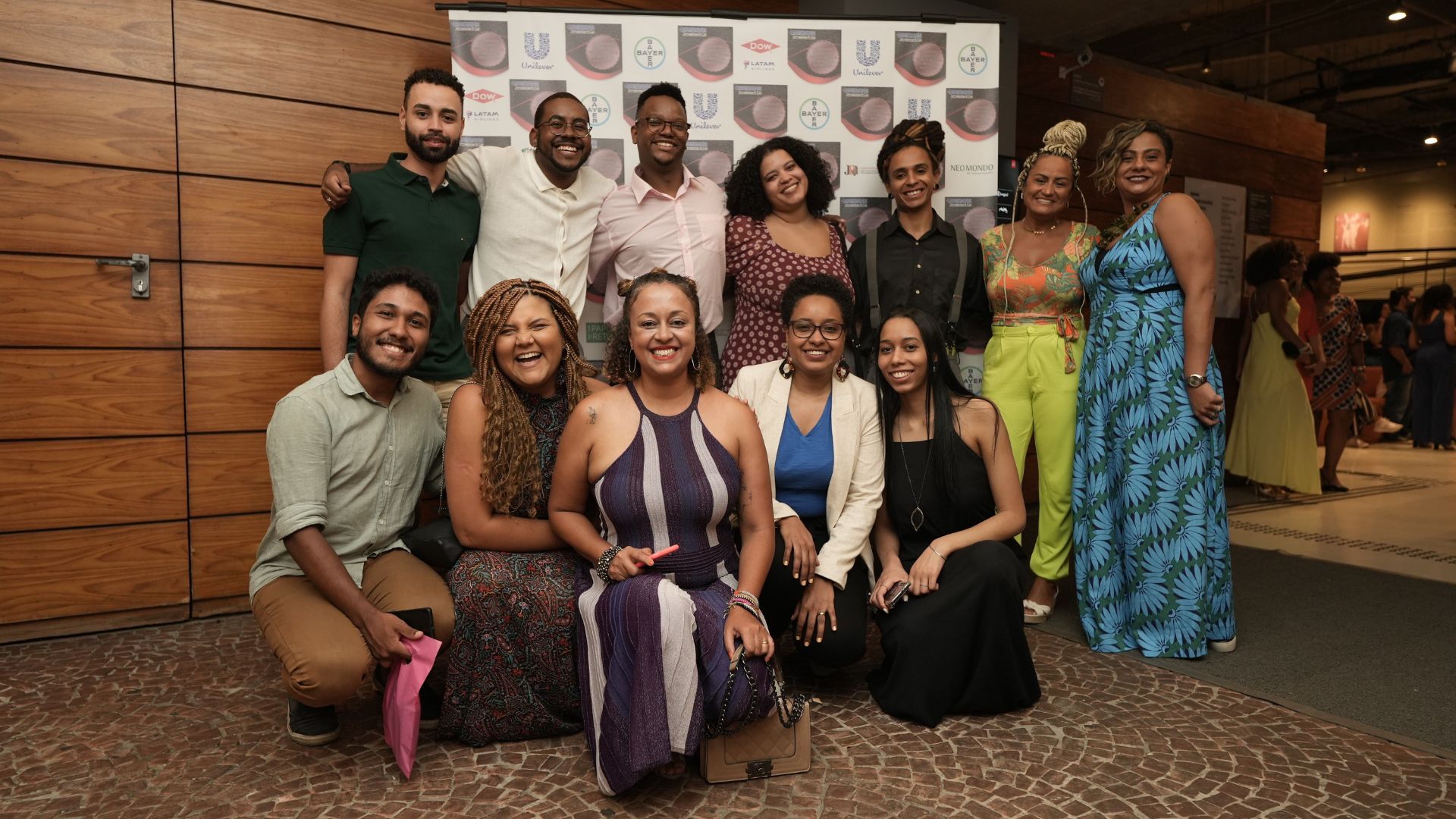 Coletivo Afrolever, atrás de um painel branco com logo Unilever e de outras empresas patrocinadoras do evento