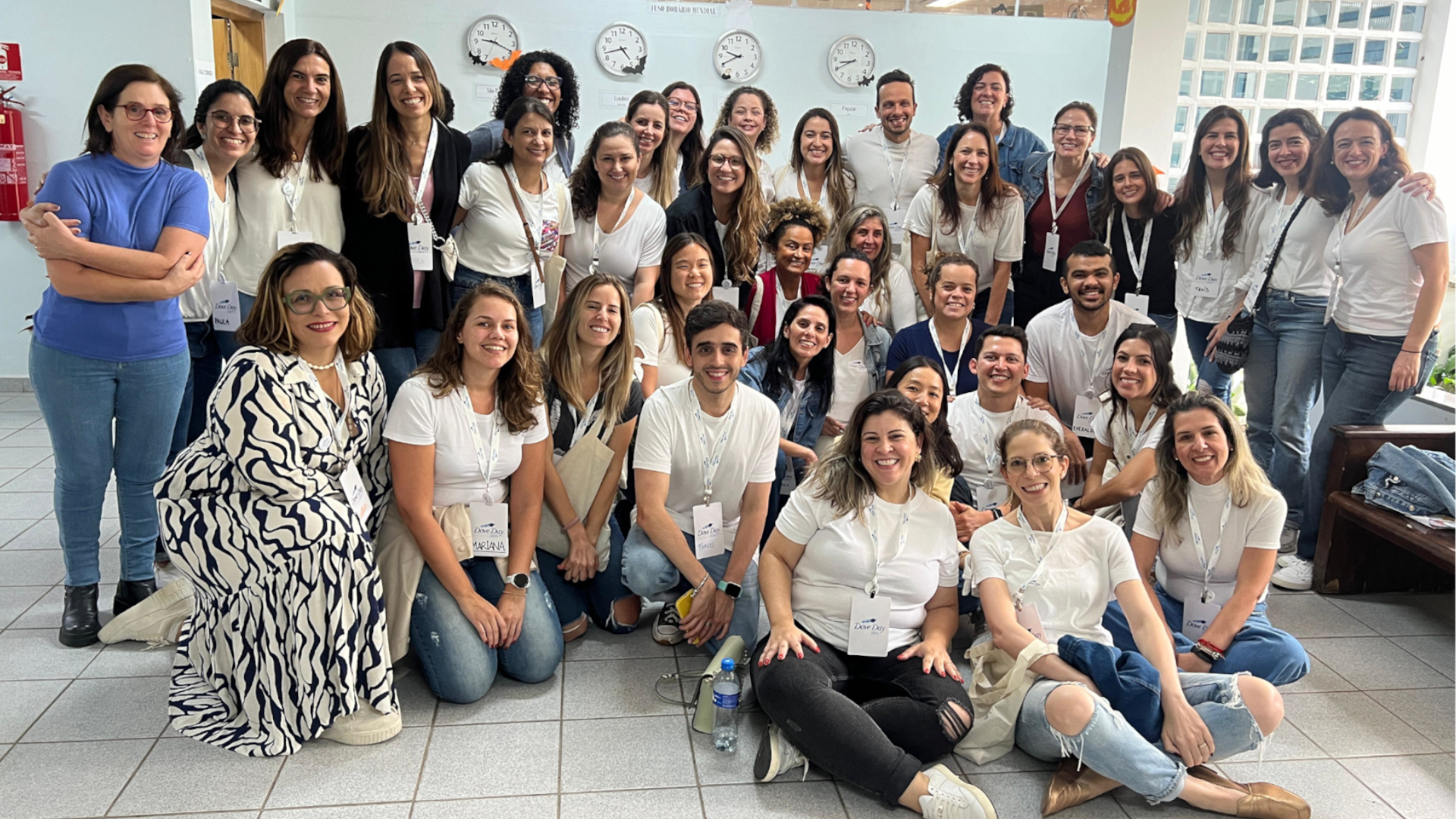 Grupo de pessoas na foto, com camisetas brancas e fundo claro.