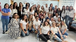 Grupo de pessoas na foto, com camisetas brancas e fundo claro.