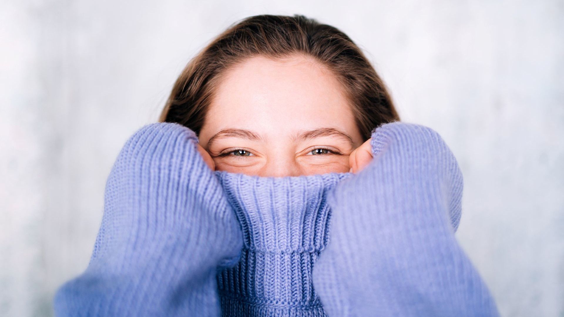 Uma mulher vestindo um suéter de gola alta de tricô na cor lavanda.