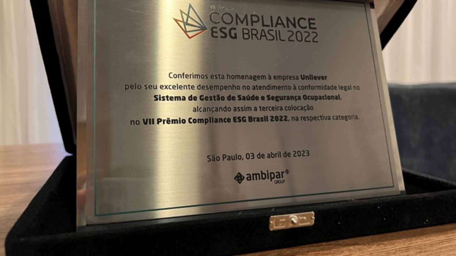 Troféu do prêmio Compliance ESG em cor bege, em uma mesa.