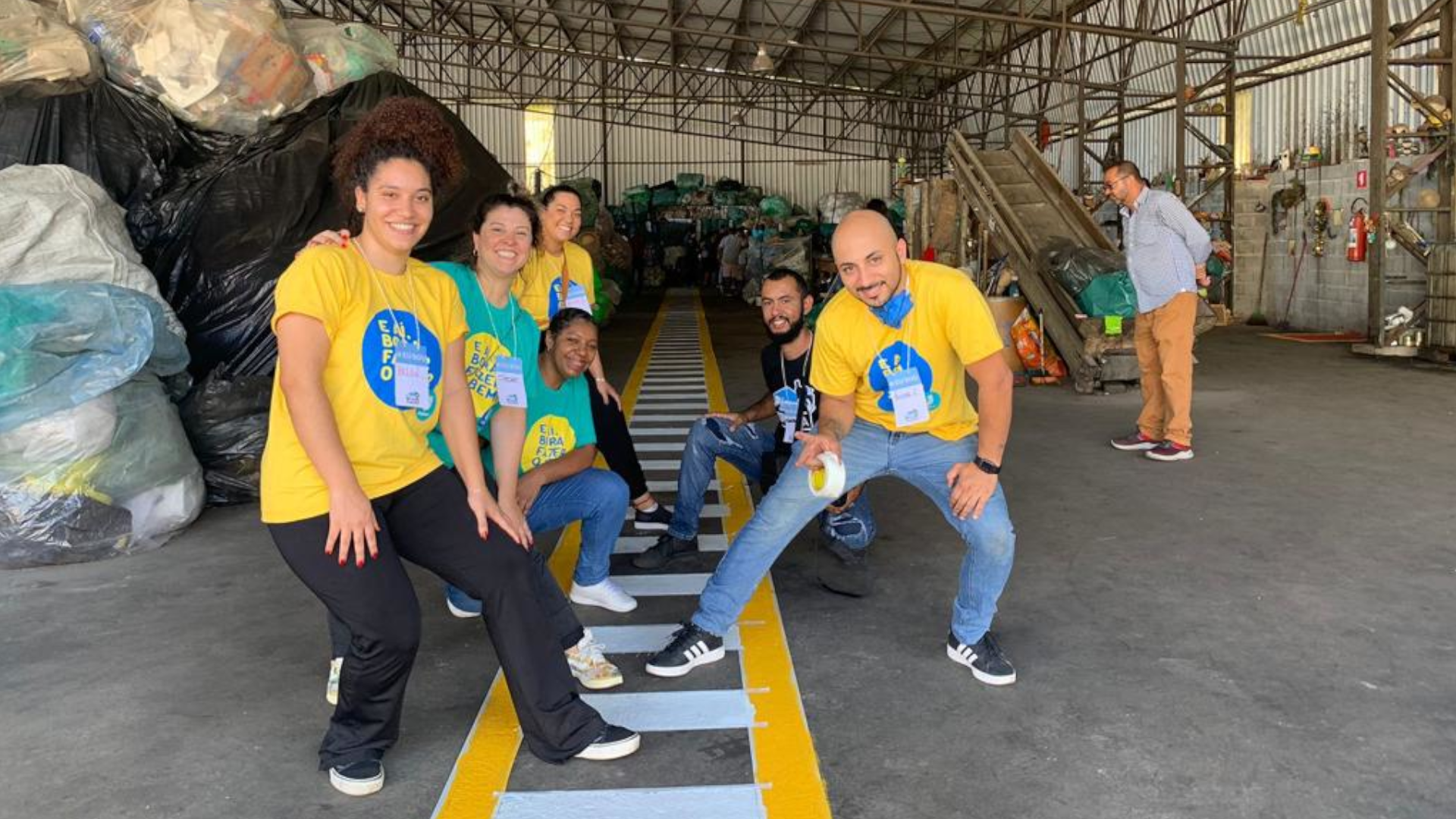 Fundo neutro, cinza, com seis pessoas juntas nas fotos e com camisetas verdes e amarelas.