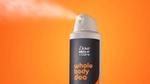 Um desodorante corporal Dove Men+Care é borrifado sobre um fundo laranja.