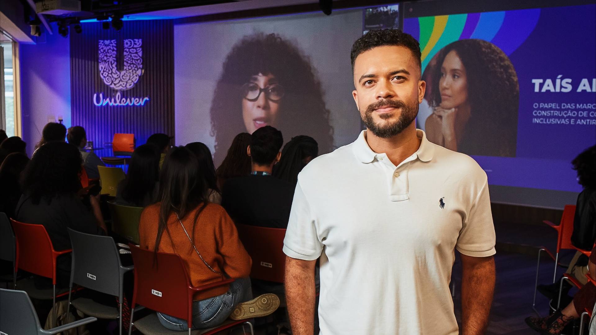 Vinicius Araújo com uma camisa branca. Fundo logo Unilever e no slide, a Taís Araújo. 