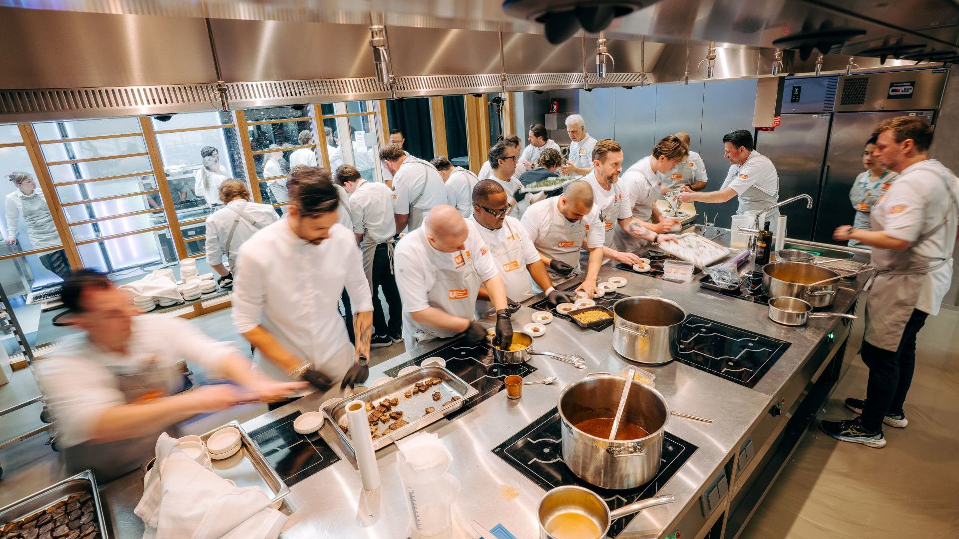 Uma equipe de chefs da Unilever Food Solutions prepara alimentos em uma cozinha movimentada, com várias panelas nos fogões.