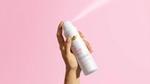 Um desodorante Dove para todo o corpo, em spray, com fragrância de framboesa e rosa, sobre um fundo rosa claro.