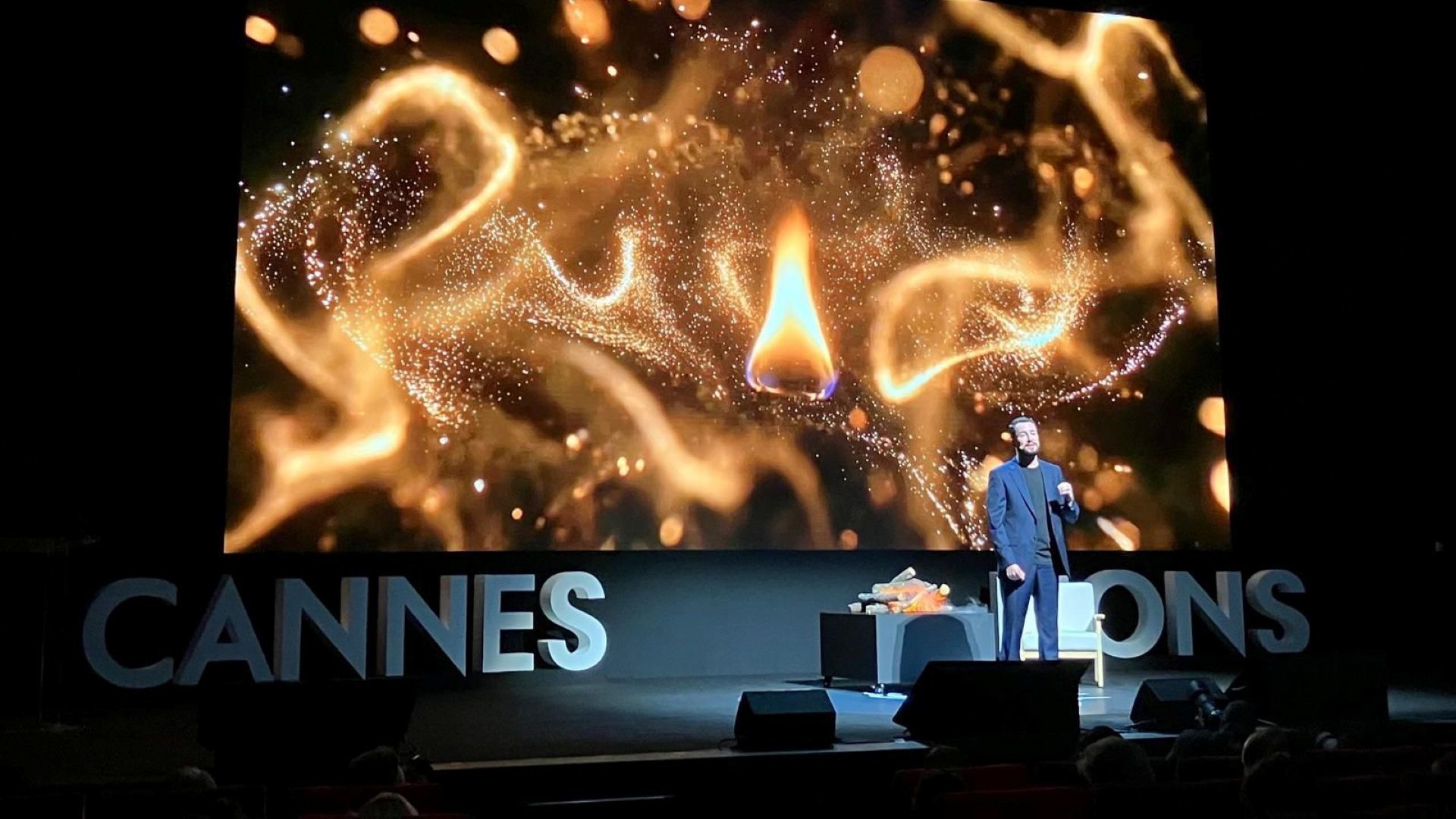 Leandro Barreto no palco do Cannes Lions, fazendo sua apresentação principal diante de uma imagem de chamas.